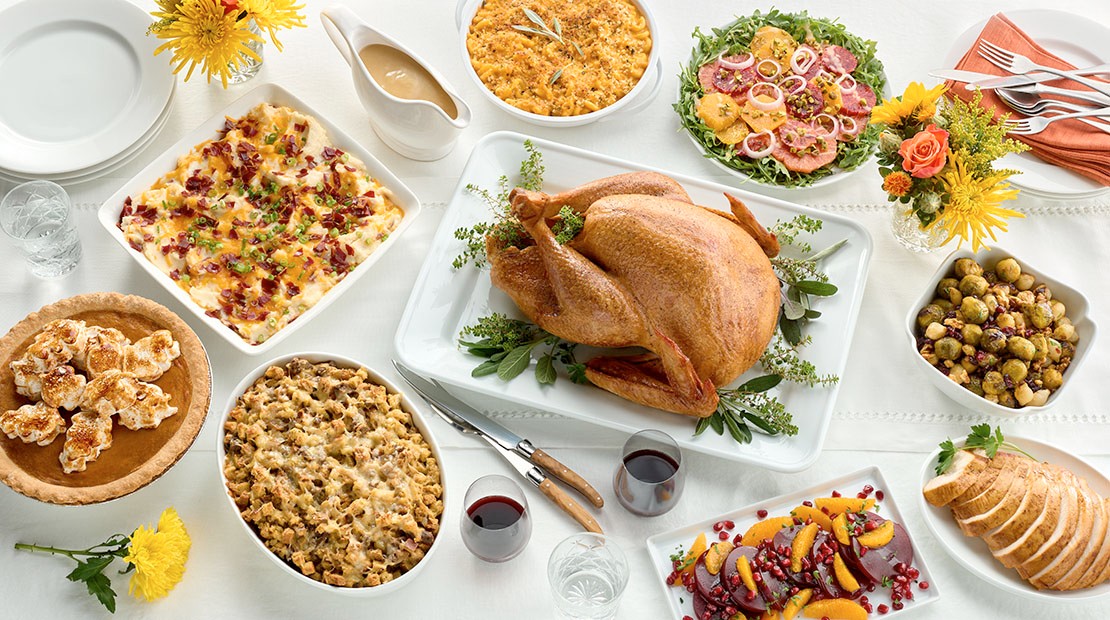 A bountiful Thanksgiving dinner table laden with a roasted turkey, side dishes, and autumnal decorations, representing the traditional Thanksgiving feast celebrated in the United States.