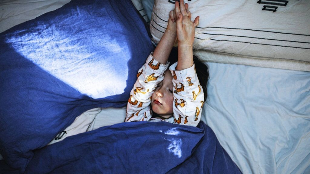 A child sleeping in bed, highlighting the nighttime increase in croup symptoms