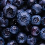 A close-up shot of fresh blueberries, some whole and some cut in half, showcasing their juicy interior.