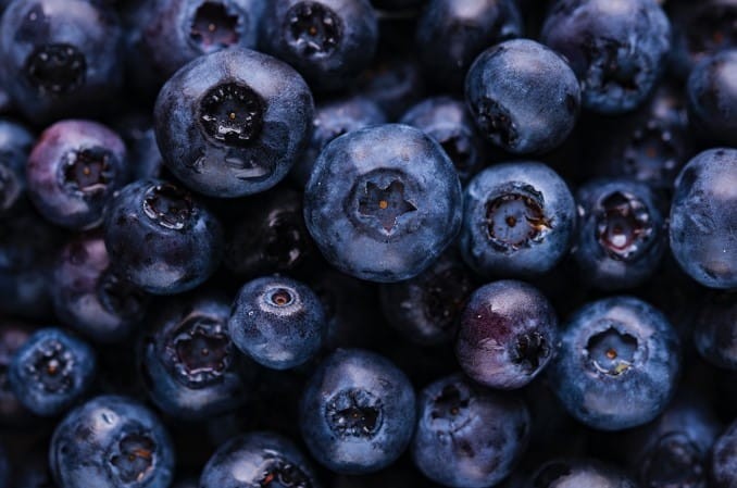 A close-up shot of fresh blueberries, some whole and some cut in half, showcasing their juicy interior.