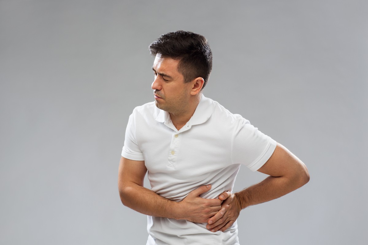 A man experiencing flank pain, holding his left side.