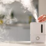 A person hand reaching to adjust a dial on a white humidifier in their home