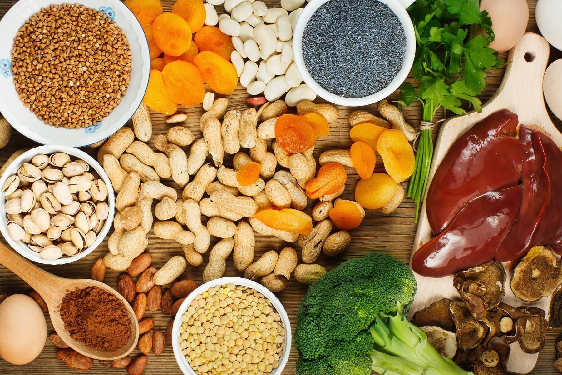 A platter of food containing apricots, peanuts, broccoli and other forods.