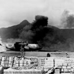 A U.S. Air Force C-130 Hercules takes off amidst smoke at Khe Sanh, Vietnam, highlighting the intense conflict of the Tet Offensive in 1968.