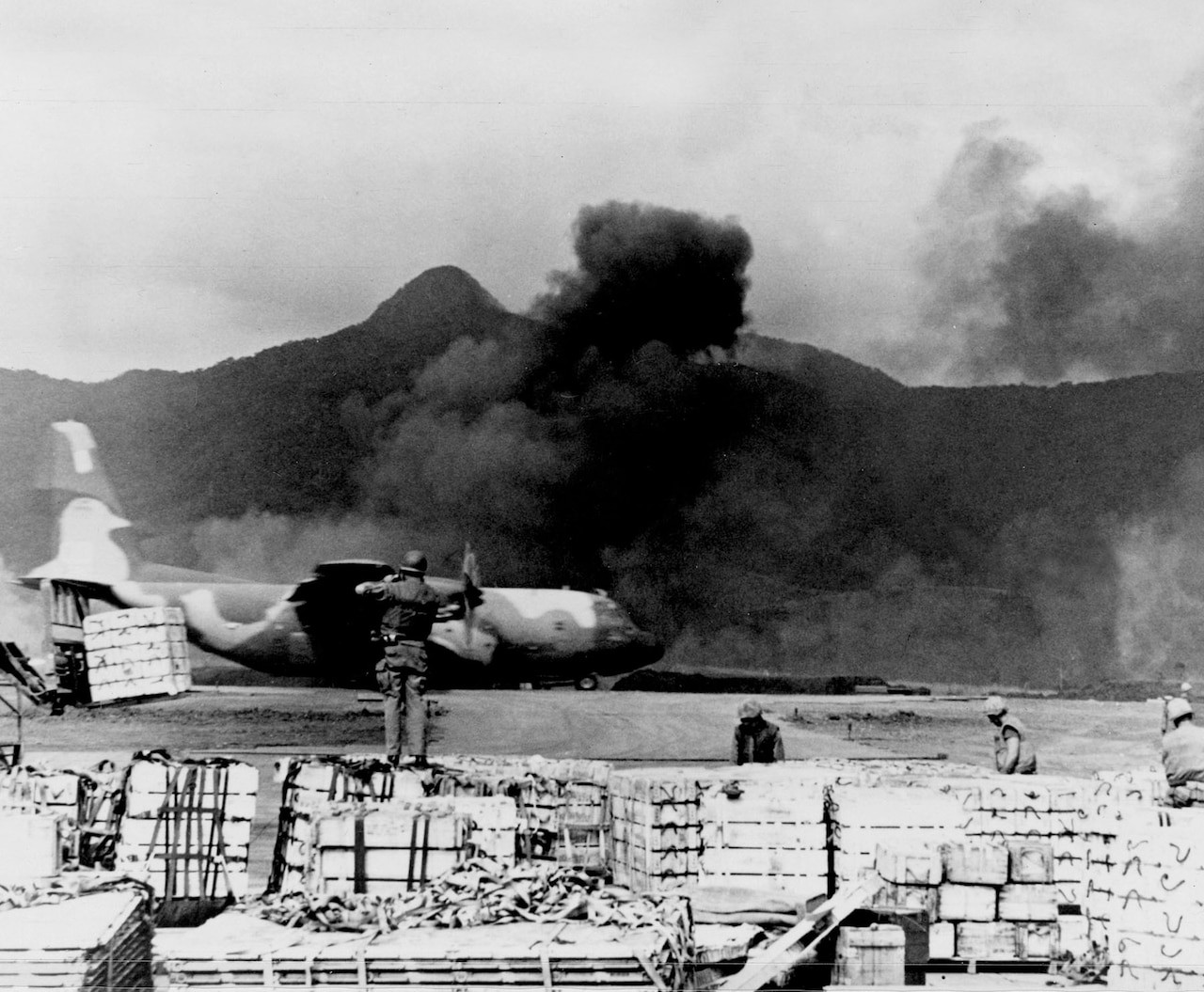 A U.S. Air Force C-130 Hercules takes off amidst smoke at Khe Sanh, Vietnam, highlighting the intense conflict of the Tet Offensive in 1968.