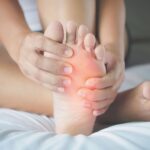 A woman examining her swollen foot, highlighting the need to understand the causes of foot swelling.