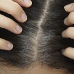 Close-up of a woman with visible grey hairs, depicting the natural process of hair turning grey with age. Understand the science behind graying hair.