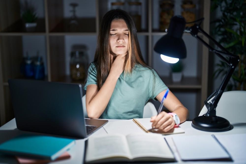 Concerned woman holding throat, possibly experiencing nighttime sore throat