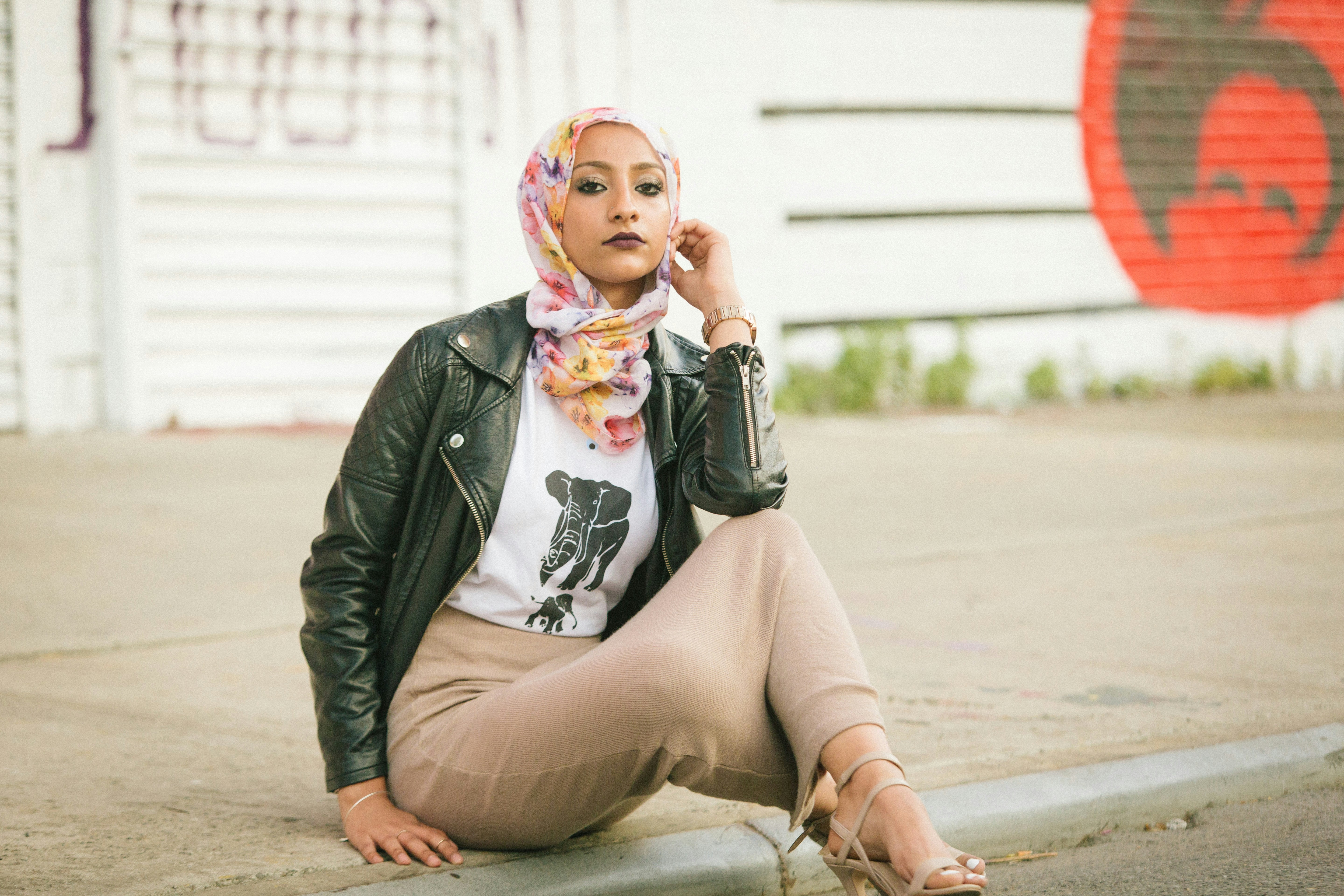 Demure woman in a black jacket in an urban setting, embodying modest fashion.