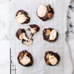 Disappointingly flat cookies on a baking sheet, a common baking problem caused by butter melting too quickly.