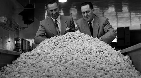 Founders of Taffy Town stand behind a large mound of salt water taffy, showcasing the scale of their candy production and history.