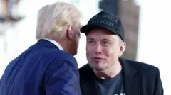 Getty Images Tesla and SpaceX CEO Elon Musk speaks with former president Donald Trump during a campaign event in Pennsylvania. Musk wears a black