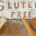 Gluten-free baking utensils and ingredients arranged on a wooden surface, highlighting the variety of options available for gluten-free cooking.