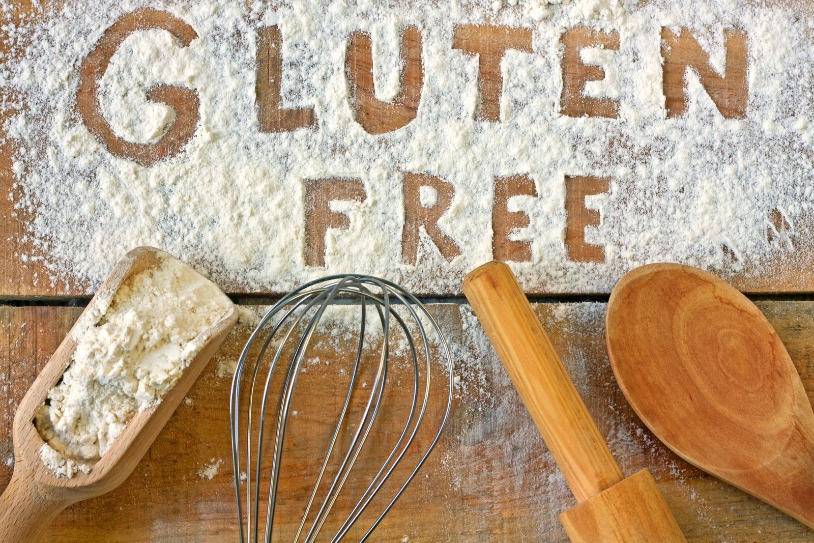 Gluten-free baking utensils and ingredients arranged on a wooden surface, highlighting the variety of options available for gluten-free cooking.