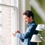 Man checking smart watch at window