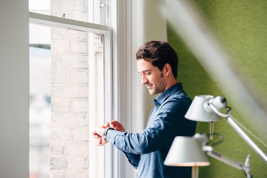 Man checking smart watch at window