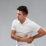 Man experiencing side pain, a common symptom with various causes like muscle strain or kidney issues, as discussed in this article.