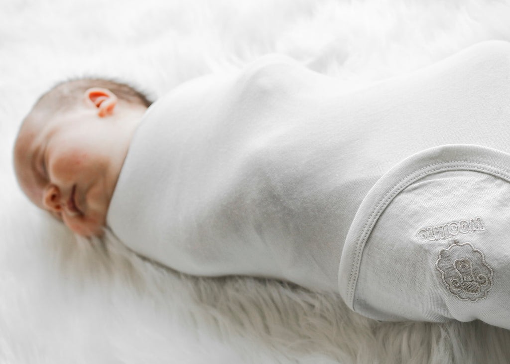 Newborn baby swaddled in beige merino wool blanket