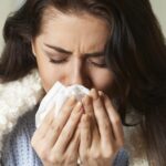 Person blowing nose with tissue