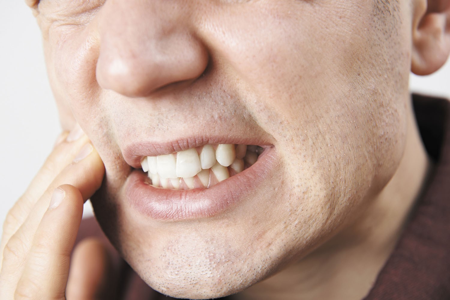 Person holding their painful jaw - Understanding the causes of jaw pain for effective diagnosis and treatment.