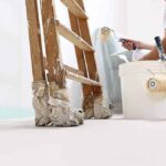 Professional painter in white uniform using a paint roller on a house exterior