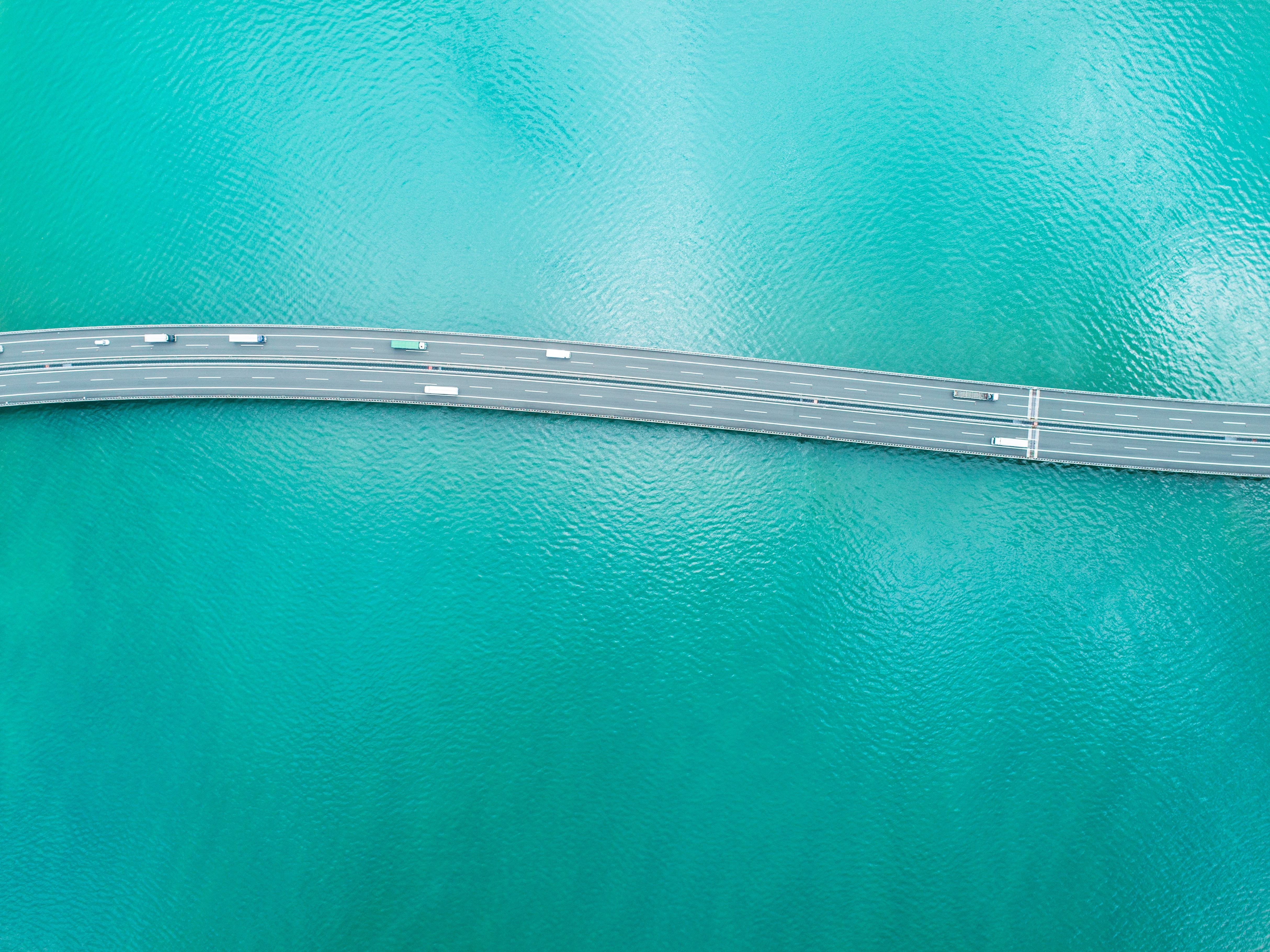 Scenic view of a highway stretching across the blue ocean, illustrating the natural color of deep ocean water due to light absorption.