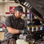 Technician performing a car battery voltage test at Jiffy Lube