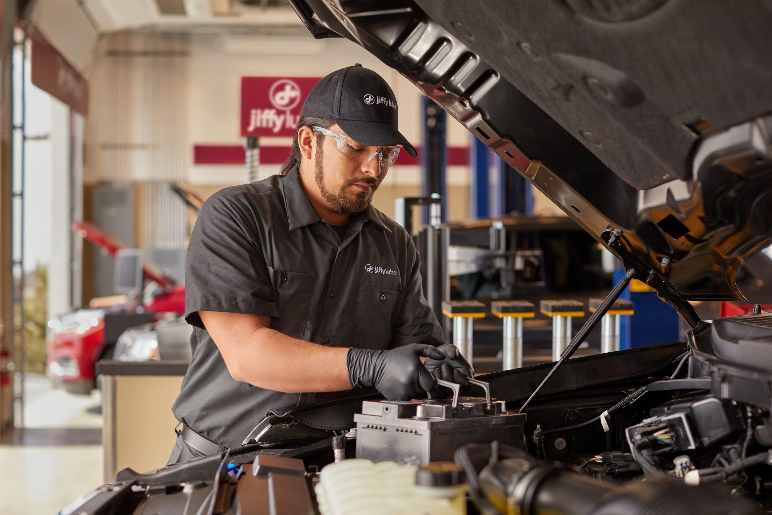 Technician performing a car battery voltage test at Jiffy Lube