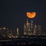 The 1 August 2023 supermoon captured by Fatih Aktas, New York City, USA. The image displays the moon in a bright orange color above the Empire State Building due to atmospheric scattering.