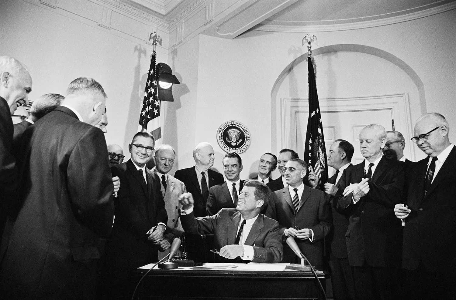 U.S. President John F. Kennedy (center, seated) signs a trade bill at the White House in Washington, D.C., on Oct. 11, 1962.