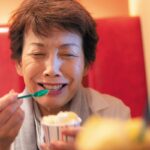 Woman grimacing and holding her forehead after experiencing brain freeze from eating ice cream, illustrating the sudden intense headache caused by rapid consumption of cold treats