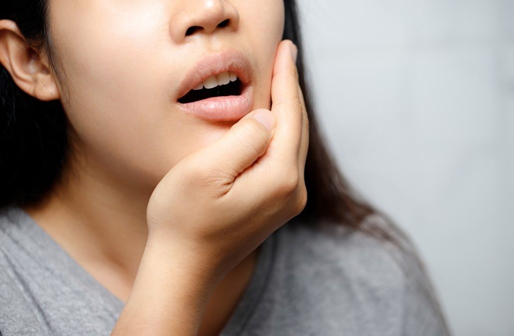 Woman holding her jaw in pain, depicting toothache