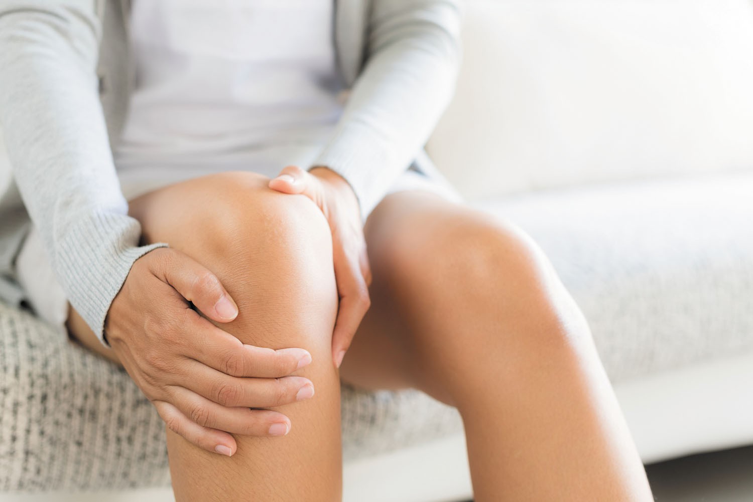 Woman holding her painful knee, illustrating patellofemoral pain syndrome