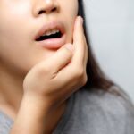 Woman holding jaw in pain, indicating toothache