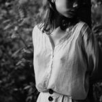 Woman in a white shirt walking in a sunlit forest, illustrating outdoor activity and potential nipple sensitivity due to environmental factors