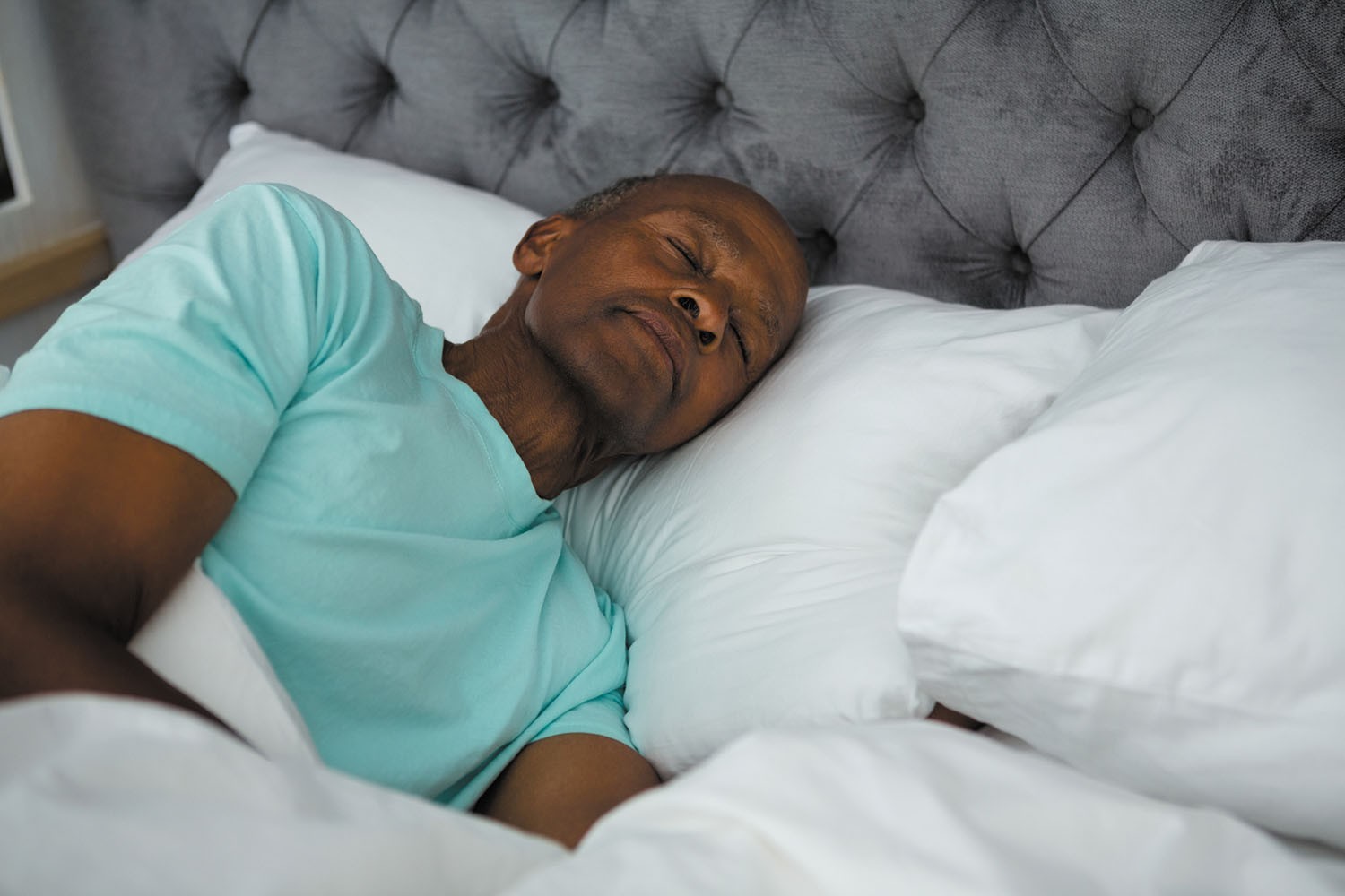 Woman waking up in bed looking at sunlight, illustrating reasons why you can't sleep through the night.