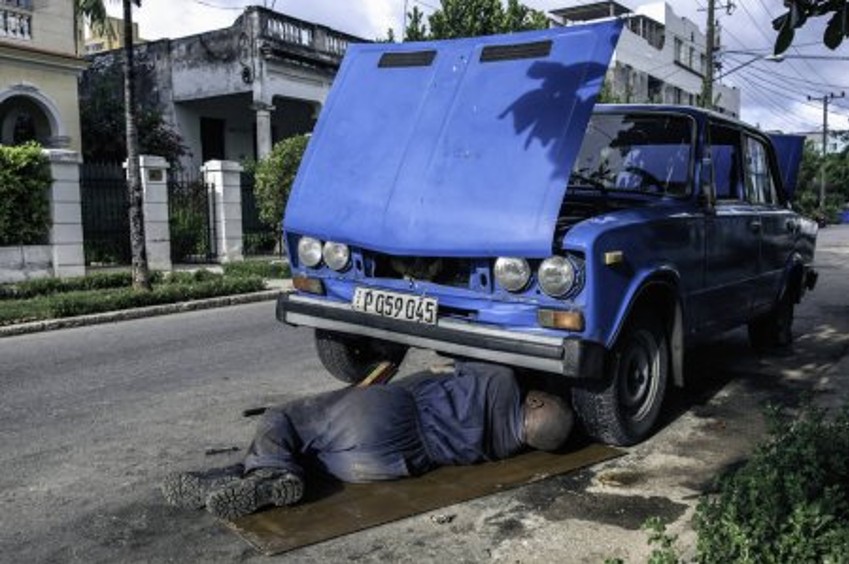 Cuban mechanic working on a vintage car engine