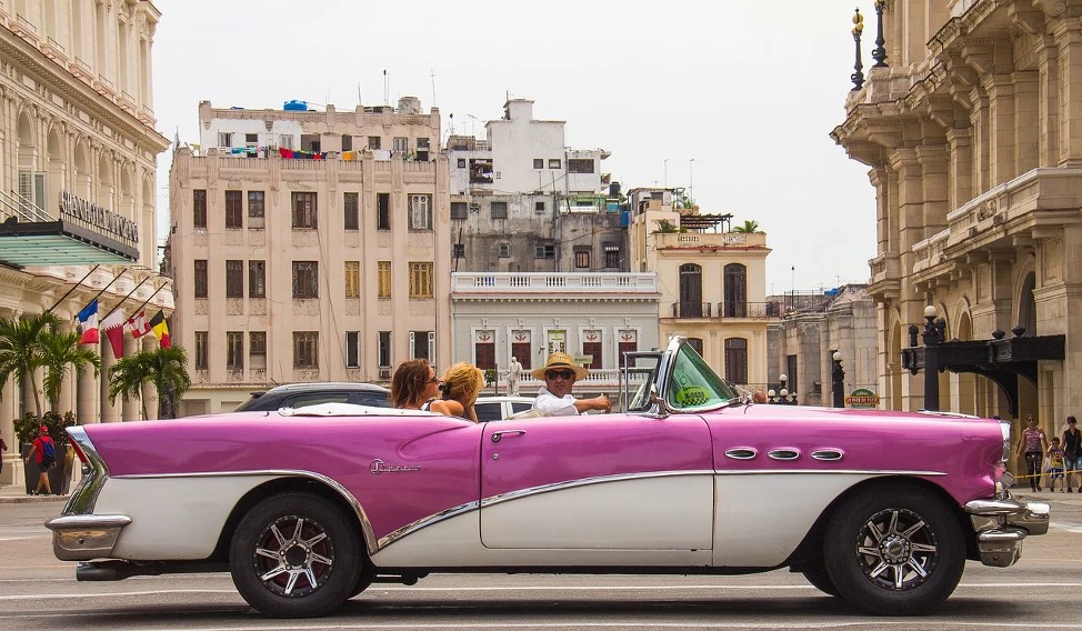A vintage convertible car with tourists in Havana